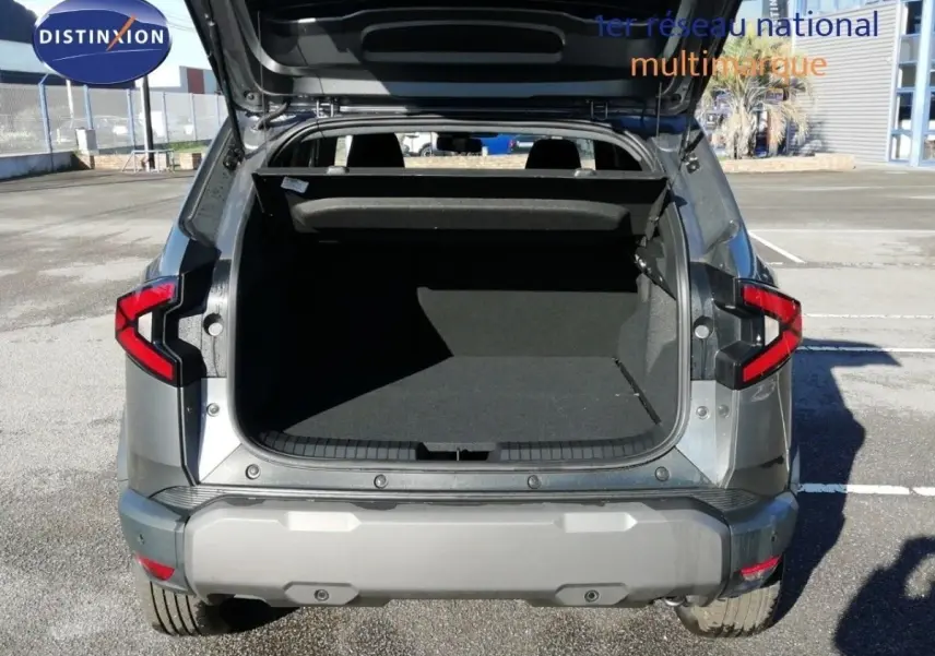 Vue arrière du Dacia Duster gris schiste métal 2026 avec coffre ouvert et feux arrière LED visibles.