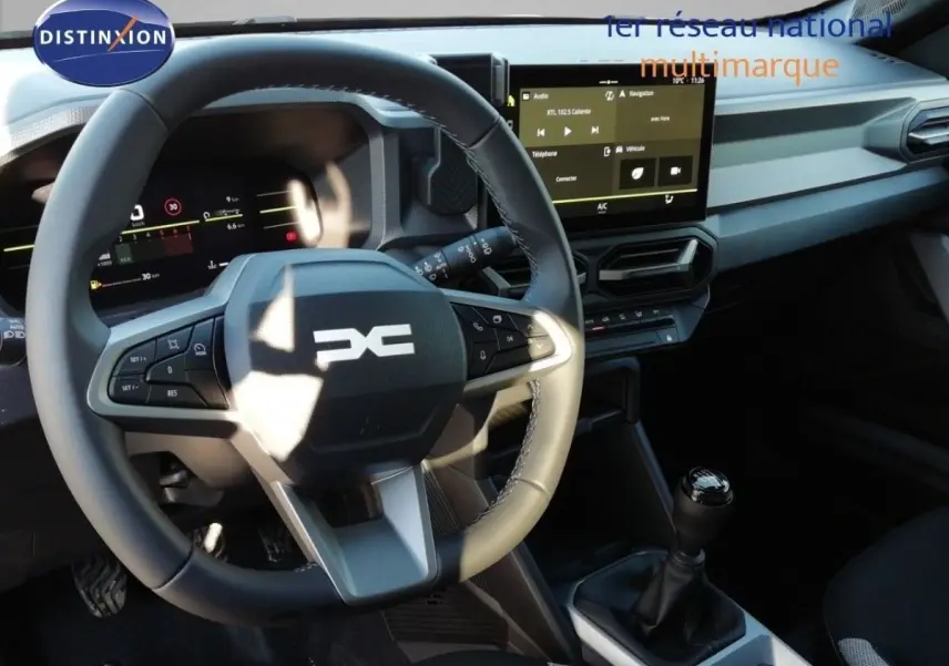 Vue intérieure centrée sur le volant multifonction et la console centrale avec levier de vitesse manuelle du Dacia Duster gris schiste.