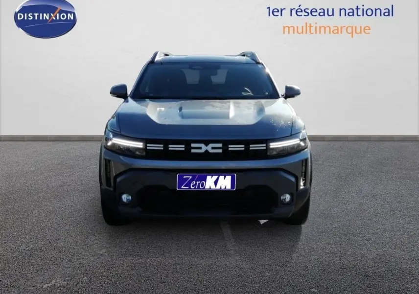 Vue frontale d'un Dacia Duster gris schiste métal 2026 avec calandre moderne et feux LED allumés.