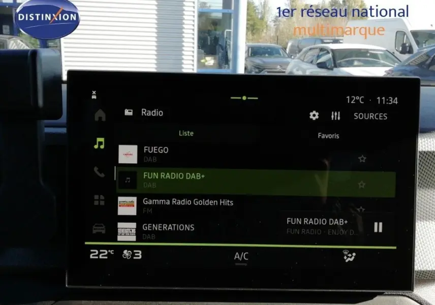 Écran tactile central du Dacia Duster gris schiste métal, affichant la radio numérique en intérieur jour.