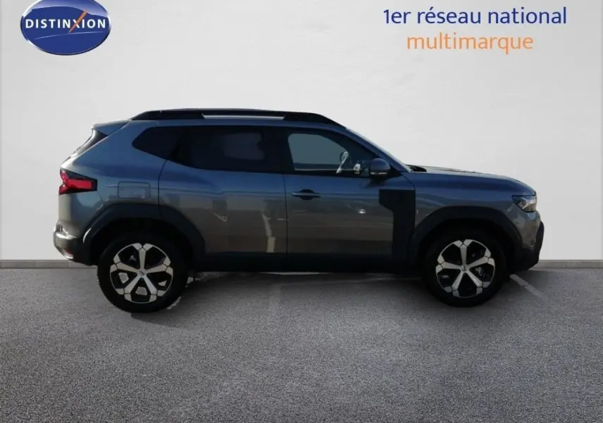 Profil latéral droit du Dacia Duster TCE MHEV gris schiste métal, soulignant ses jantes bi-ton et ses lignes robustes.