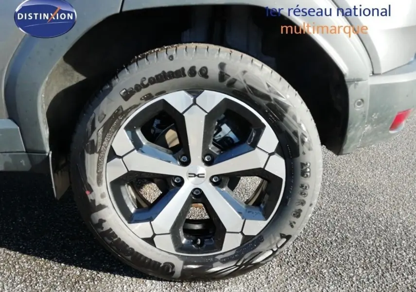 Gros plan sur la roue avant droite du Dacia Duster gris schiste métal, jante bi-ton noire et grise.