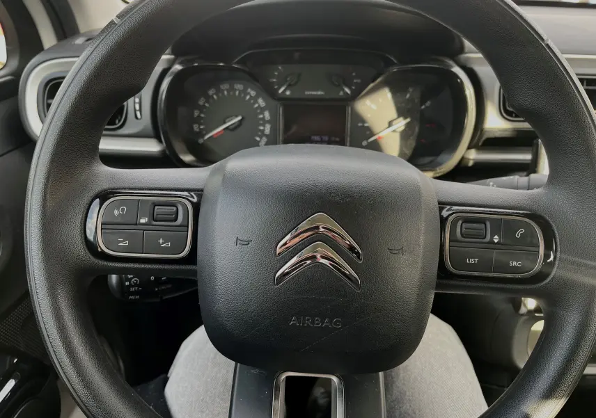 Vue rapprochée du volant noir de la Citroën C3 2019 avec commandes intégrées et tableau de bord en arrière-plan.