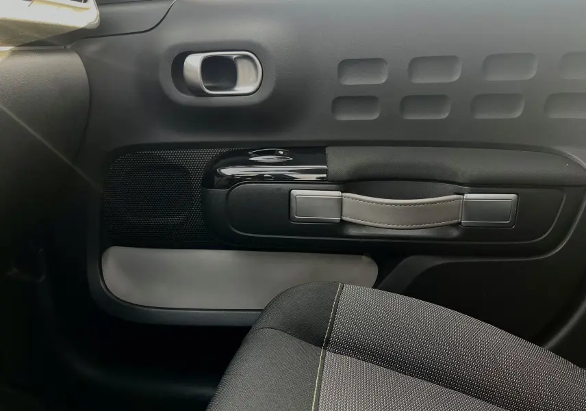 Détail de la porte intérieure côté droit d'une Citroën C3 blanche 2019, avec poignée en cuir et tissu noir du siège visible.