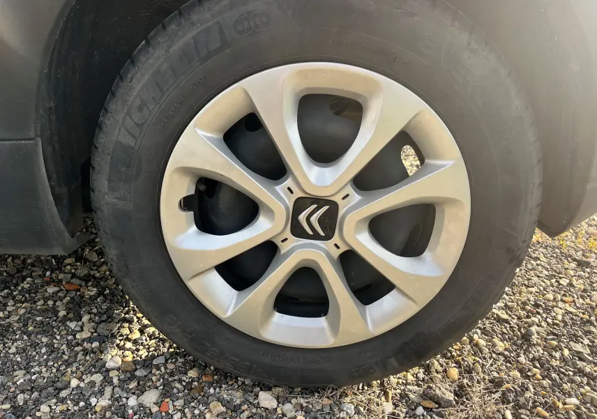 Gros plan sur la roue avant gauche d'une Citroën C3 blanche de 2019, mettant en valeur la jante aluminium et le logo Citroën.