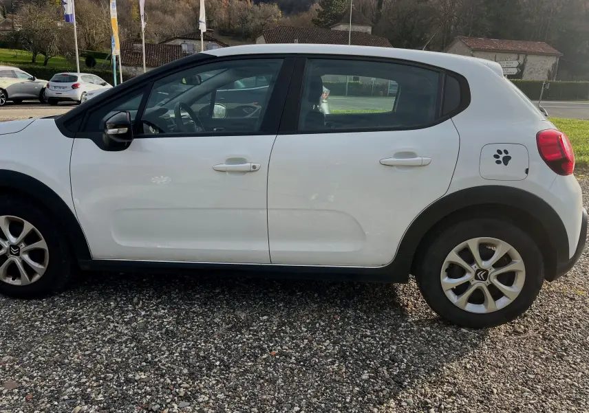 Vue de profil côté gauche d'une Citroën C3 blanche de 2019 avec autocollant patte de chien sur la trappe à carburant.