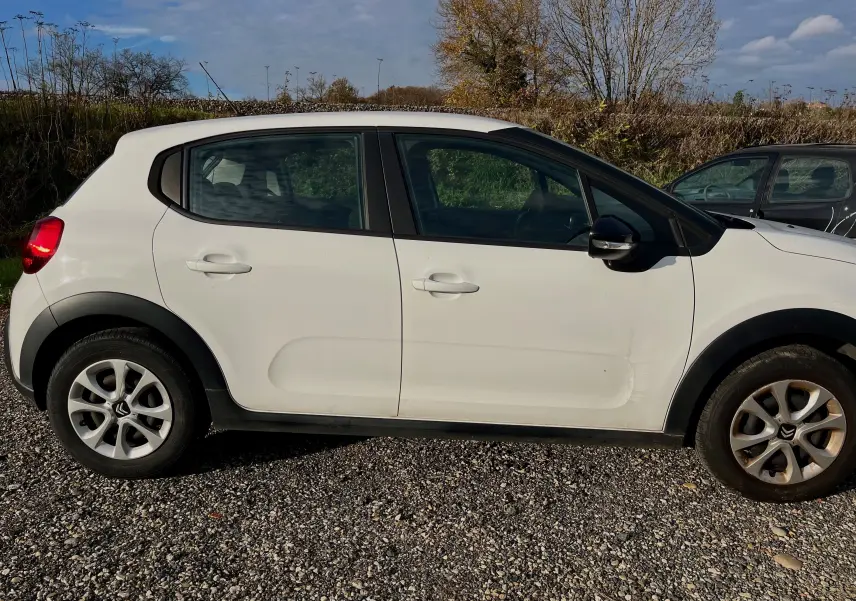 Profil côté gauche d'une Citroën C3 blanche 2019 avec jantes alliage et protections noires sur les passages de roues.