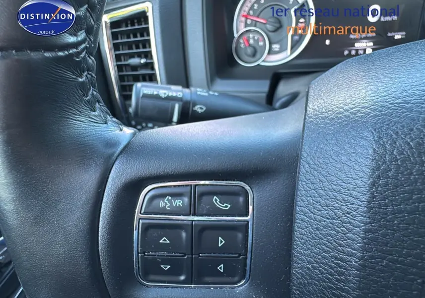 Gros plan sur le volant noir du Dodge RAM 2020 montrant les commandes vocales et téléphone côté gauche.