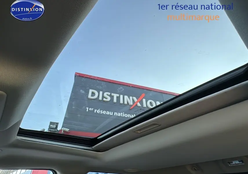 Vue intérieure du toit ouvrant panoramique du Dodge RAM 5.7 V8 noir, montrant le ciel et une enseigne extérieure.