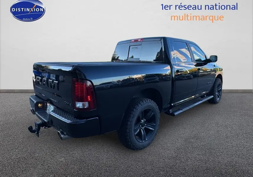 Vue 3/4 arrière droite d’un Dodge RAM 5.7 V8 Crew Sport noir brillant avec jantes noires et attelage.