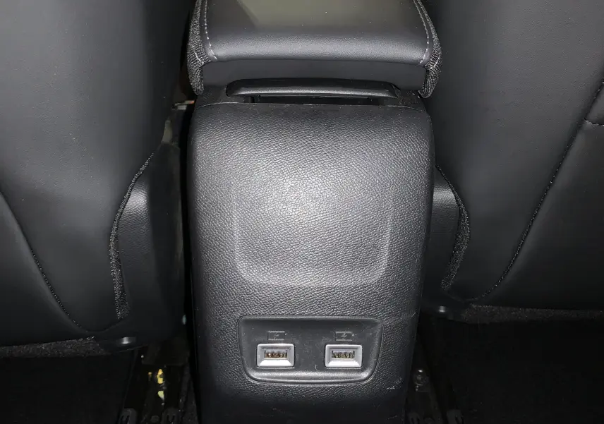 Vue rapprochée de la console arrière noire avec deux ports USB entre les sièges avant d’une Peugeot 208 gris.
