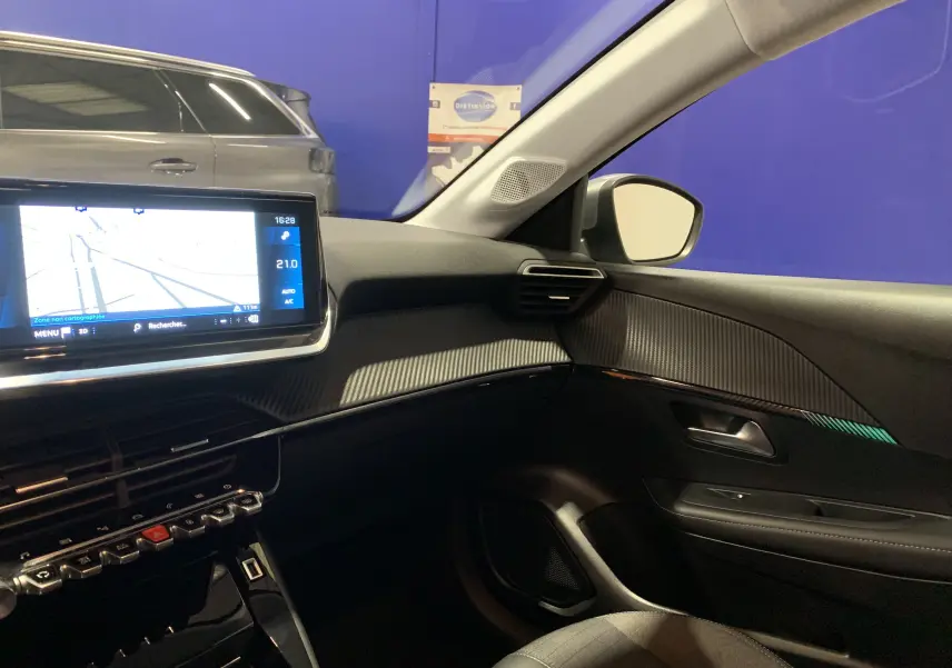 Vue intérieure côté passager de la Peugeot 208 gris, avec écran GPS tactile et tableau de bord moderne.