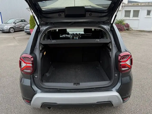 Vue arrière ouverte du Dacia Duster gris comète 2022, mettant en valeur le coffre spacieux et les feux arrière LED distinctifs.