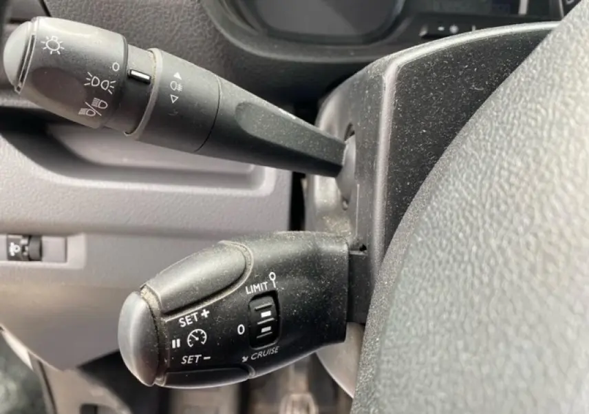 Gros plan sur les commandes au volant du Citroën Jumpy blanc 2019, montrant les leviers de régulateur et de feux.