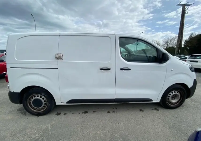 Vue de profil côté droit d’un utilitaire Citroën Jumpy blanc avec porte coulissante et roues acier.