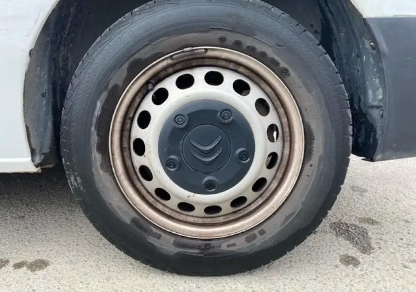 Gros plan sur la roue avant gauche d’un Citroën Jumpy blanc, jante acier avec logo Citroën noir au centre.
