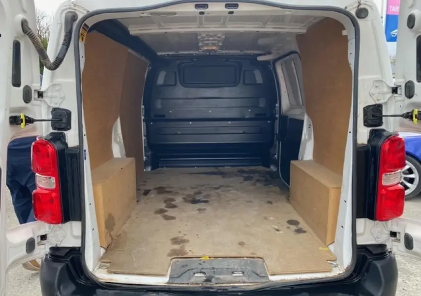Vue arrière ouverte du Citroën Jumpy blanc 2019 montrant l’intérieur utilitaire avec habillage bois et plancher usé.