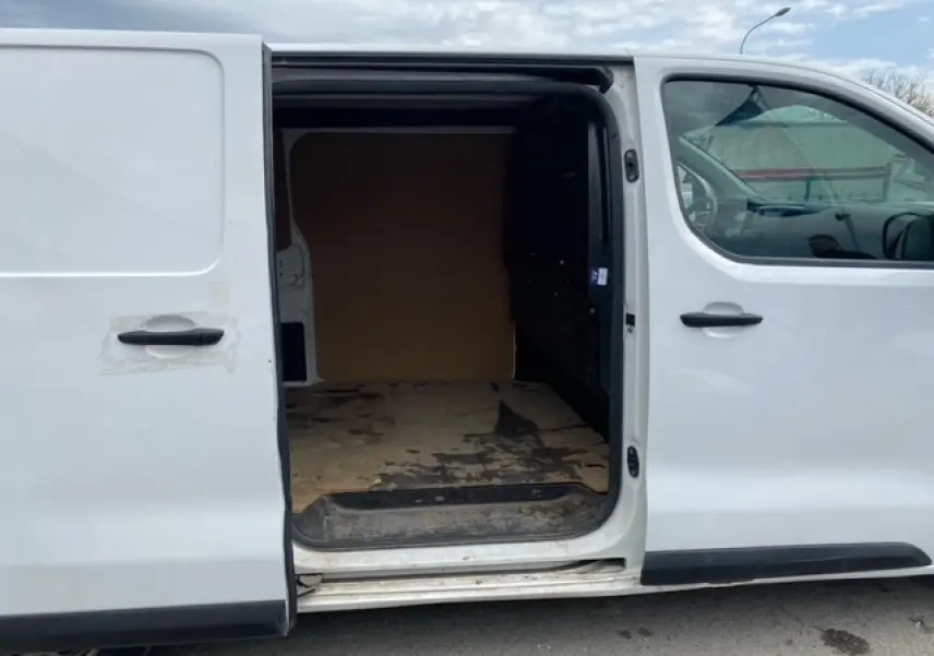 Vue latérale gauche d’un Citroën Jumpy blanc avec porte coulissante ouverte montrant l’intérieur utilitaire en bois.