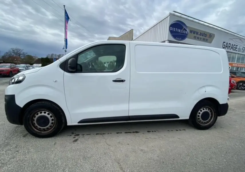 Vue de profil côté gauche d'un utilitaire Citroën Jumpy blanc, avec porte latérale coulissante et jantes acier noires.