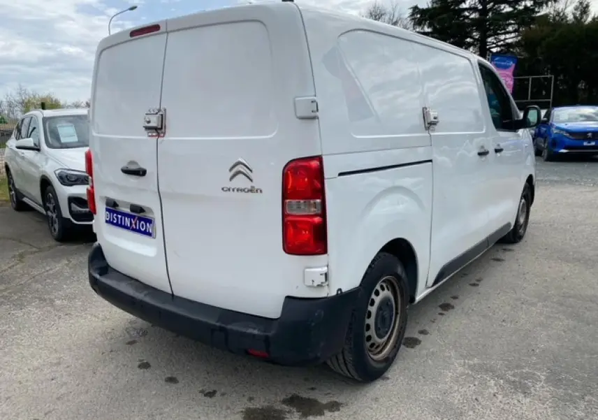 Vue 3/4 arrière droite d’un utilitaire Citroën Jumpy blanc, portes arrière battantes et porte latérale coulissante visibles.