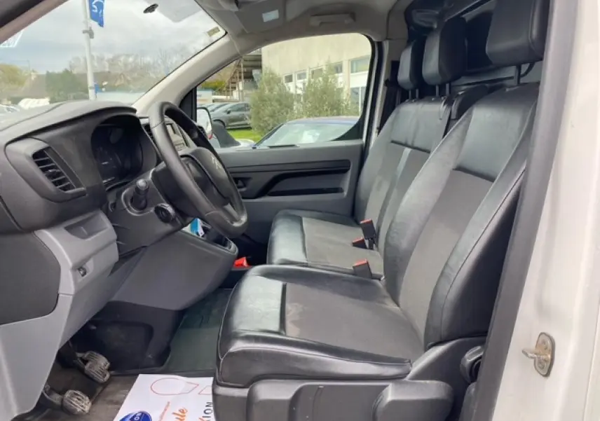 Vue intérieure côté conducteur du Citroën Jumpy blanc 2019, sièges mixtes TEP/tissu noirs et tableau de bord visible.