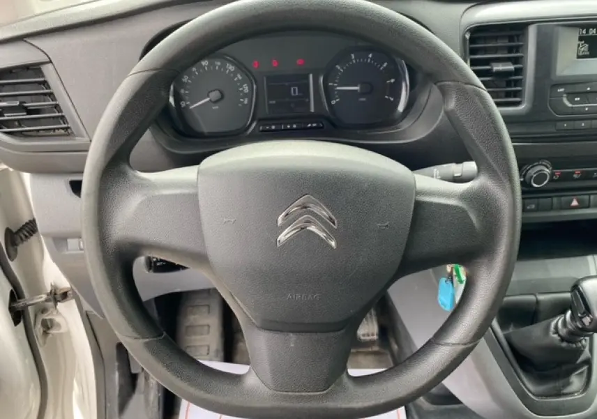 Vue intérieure centrée sur le volant noir du Citroën Jumpy blanc de 2019 avec tableau de bord et levier de vitesses manuelle.