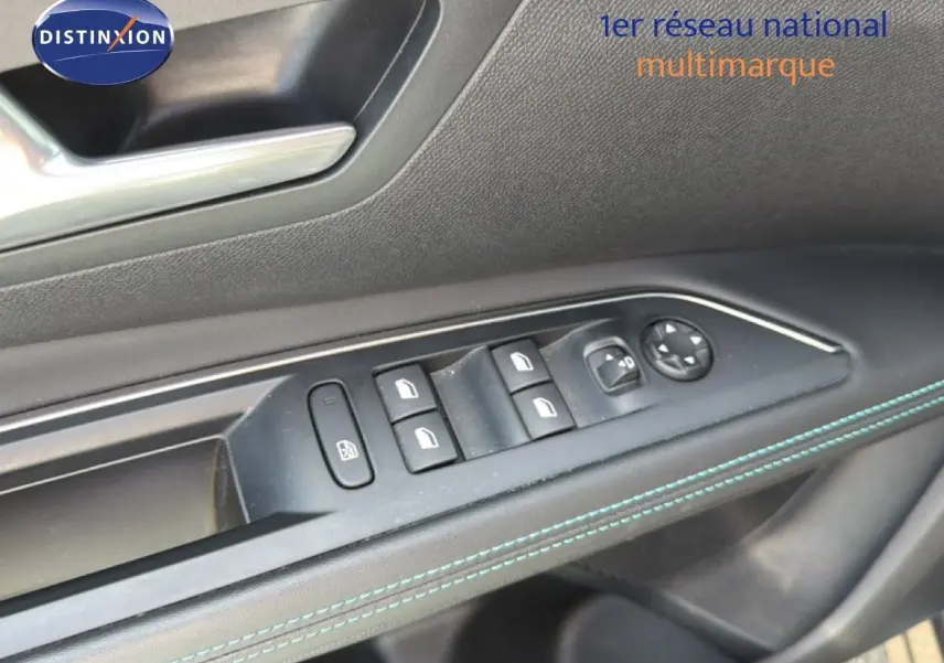 Gros plan sur la commande des vitres côté gauche du Peugeot 5008 2023 gris Platinium avec surpiqûres bleues.