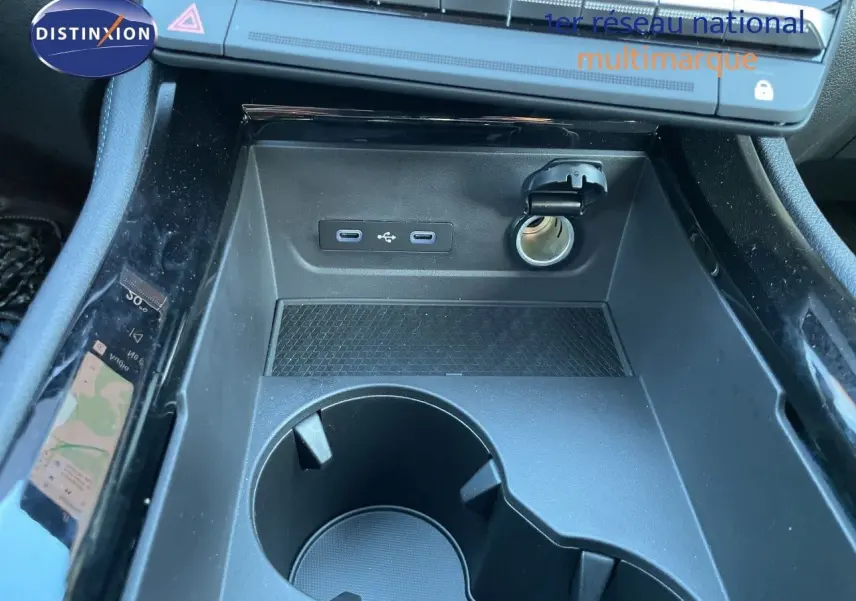 Gros plan sur la console centrale noire du Renault Austral E-Tech, montrant prises USB, allume-cigare et porte-gobelets.