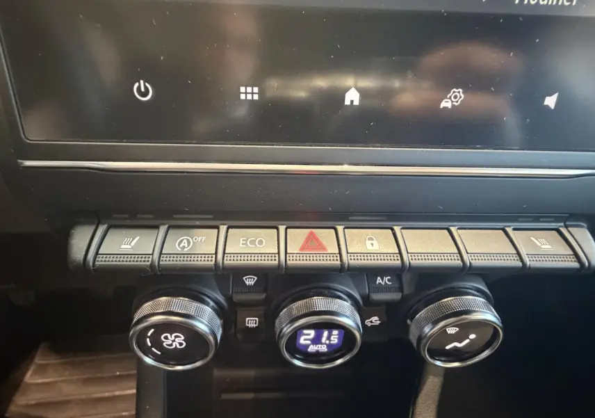 Vue rapprochée de la console centrale de la Renault Clio blanche 2024, montrant les commandes de climatisation et boutons fonctionnels.