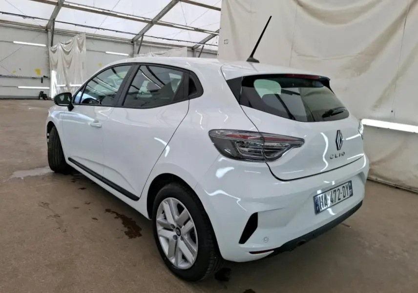 Renault Clio blanche vue 3/4 arrière droit, avec feux arrière LED et jantes alliage 16 pouces dans un garage.
