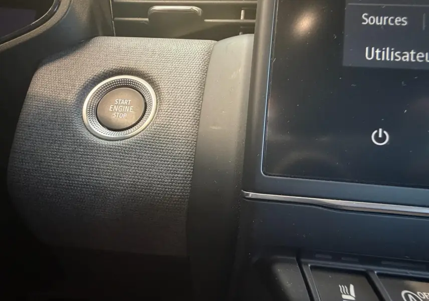 Détail intérieur du bouton Start Engine Stop sur la planche de bord noire texturée de la Renault Clio 2024.