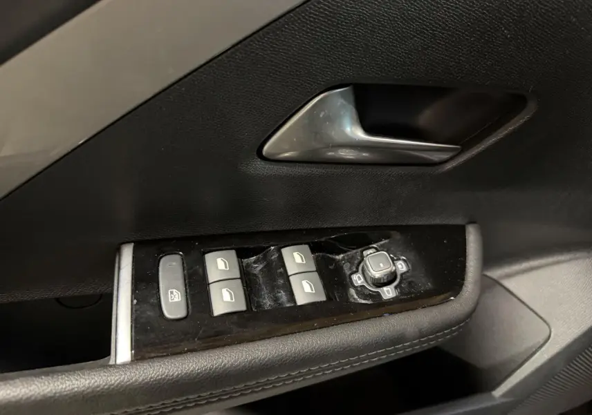 Gros plan sur la commande des vitres et rétroviseurs côté gauche de la porte intérieure noire de l'Opel Astra gris foncé.