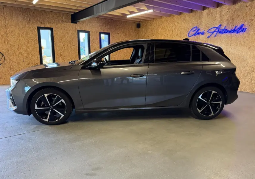 Opel Astra 2024 gris foncé vue de profil côté gauche, jantes alliage noires et vitres surteintées.