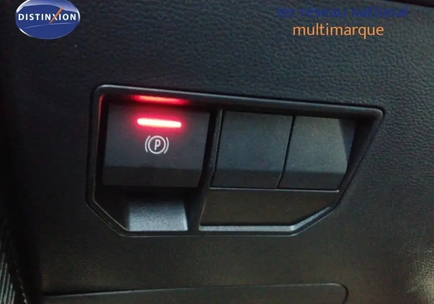 Gros plan sur le bouton de frein à main électrique allumé dans l’habitacle du Dacia Duster gris schiste métal.