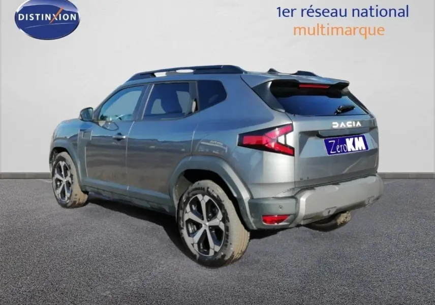 Vue 3/4 arrière droite d'un Dacia Duster gris schiste métal avec jantes bi-ton et feux arrière LED distinctifs.