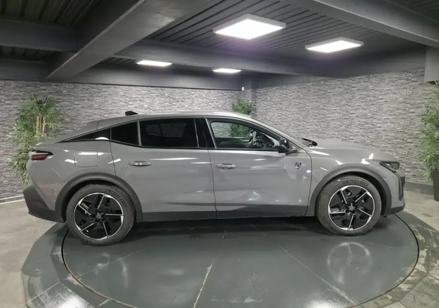 Profil côté gauche de la Peugeot 408 gris métallisé 2024 avec jantes alliage 19 pouces et toit noir Mistral.