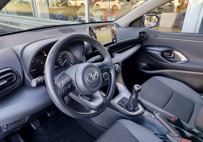 Vue intérieure côté conducteur de la Toyota Yaris blanche 2023, avec volant multifonction et boîte manuelle visible.