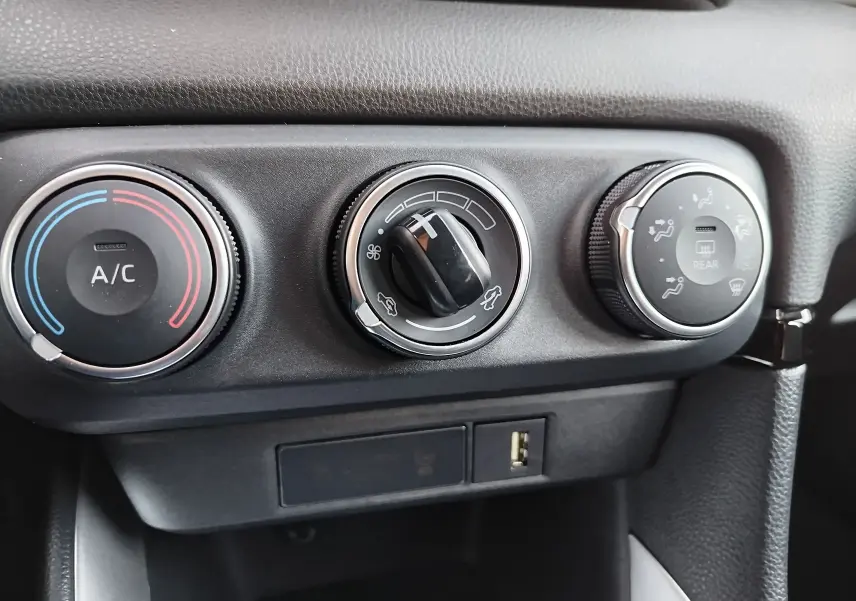 Gros plan sur les commandes de climatisation noires et grises de la Toyota Yaris blanche, version Dynamic Business 2023.