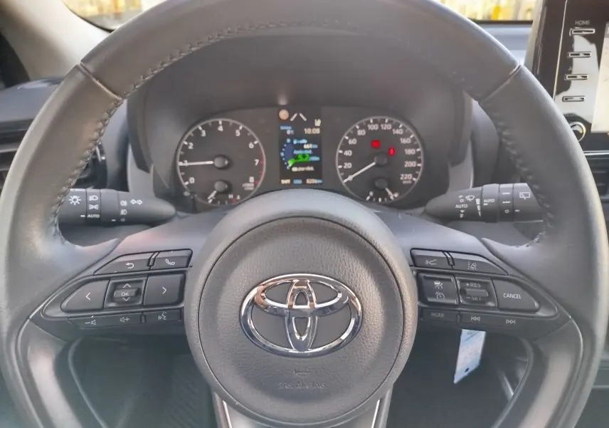 Vue rapprochée du volant noir de la Toyota Yaris 2023 avec commandes intégrées et tableau de bord digital.