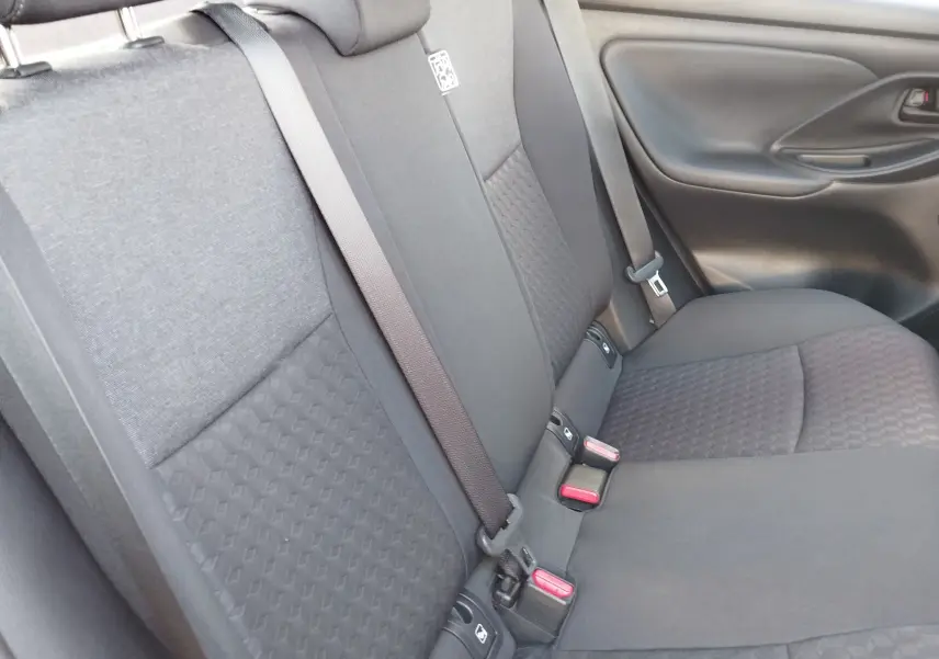 Vue intérieure du siège arrière droit de la Toyota Yaris 2023, tissu gris foncé avec ceinture de sécurité visible.