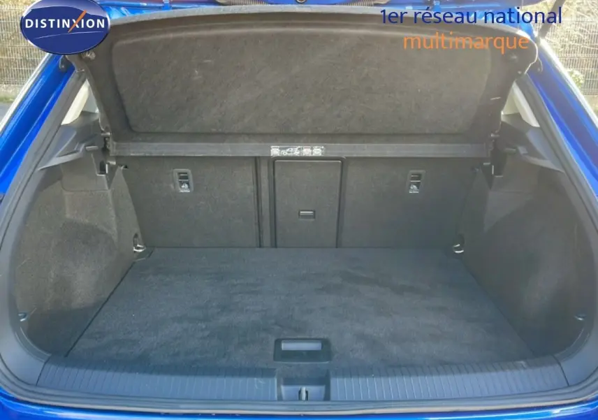 Coffre ouvert vu de l'arrière d'un Volkswagen T-Roc bleu Ravenna, montrant un espace de chargement propre et spacieux.