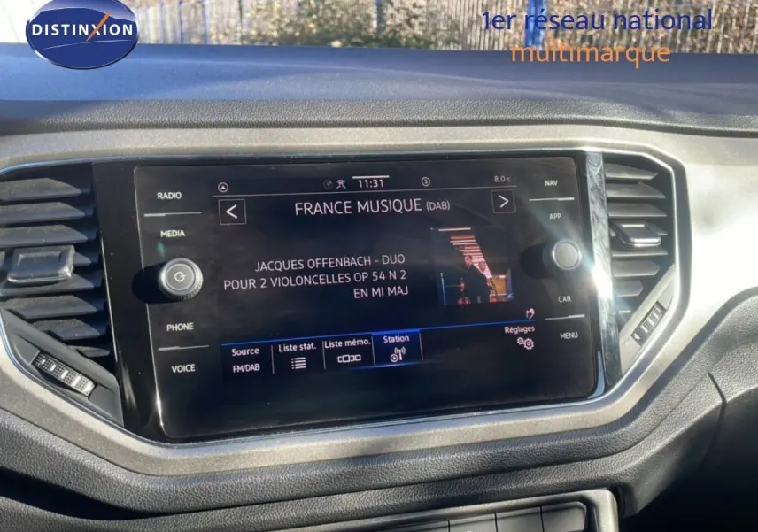 Écran tactile central du tableau de bord du Volkswagen T-Roc 1.5 TSI bleu, affichant une station radio France Musique.