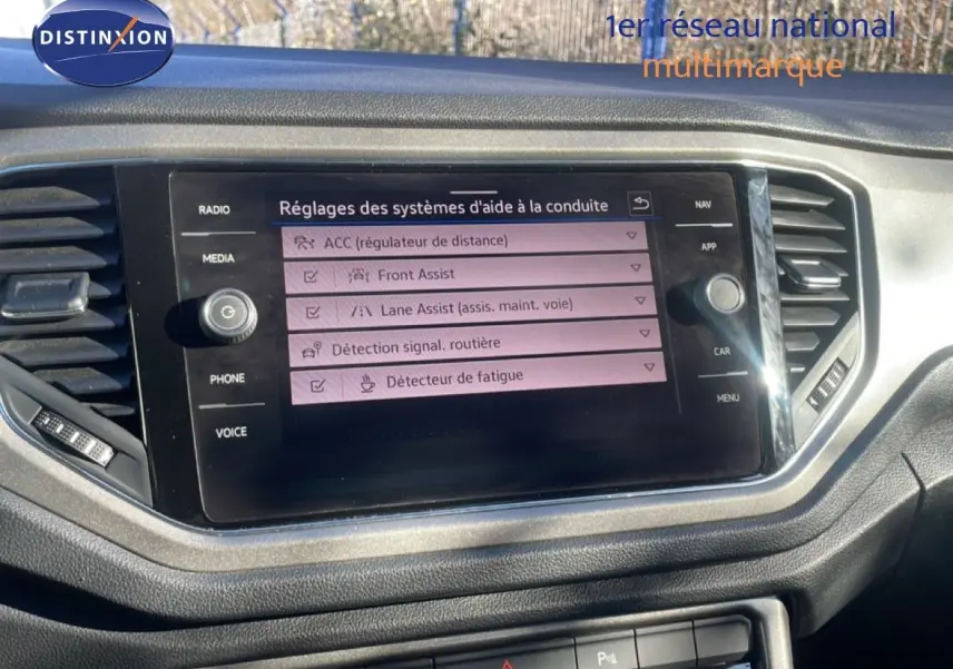 Écran central du tableau de bord du Volkswagen T-Roc 1.5 TSI bleu, affichant les réglages d’aides à la conduite.