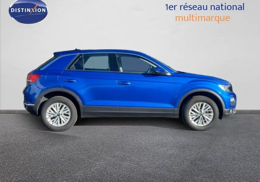 Profil droit d'un Volkswagen T-Roc bleu Ravenna métallisé, SUV compact avec jantes alliage et détails noirs.
