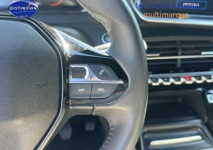 Gros plan sur le volant multifonction noir de la Peugeot 2008 1.2 100 Allure avec commandes audio et téléphone intégrées.