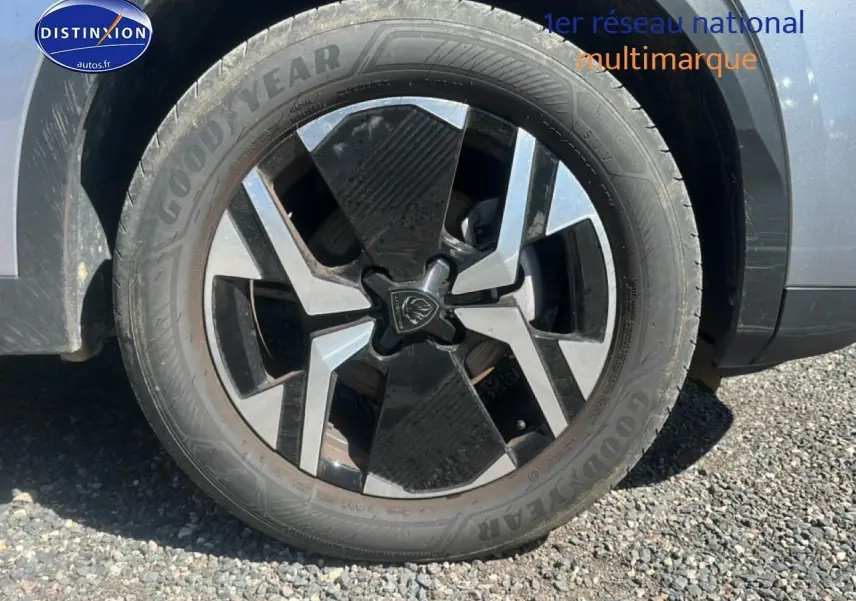 Gros plan sur la roue avant droite du Peugeot 2008 gris artense avec jante alu bicolore et logo lion central.