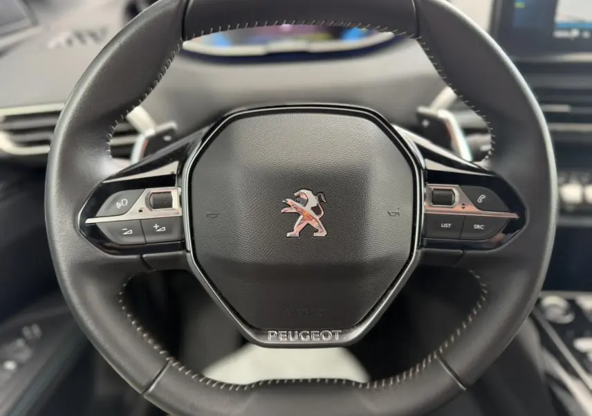 Volant cuir noir Mistral avec logo Peugeot au centre, vue frontale du poste de conduite du 3008 Plug-in Hybrid 2024.