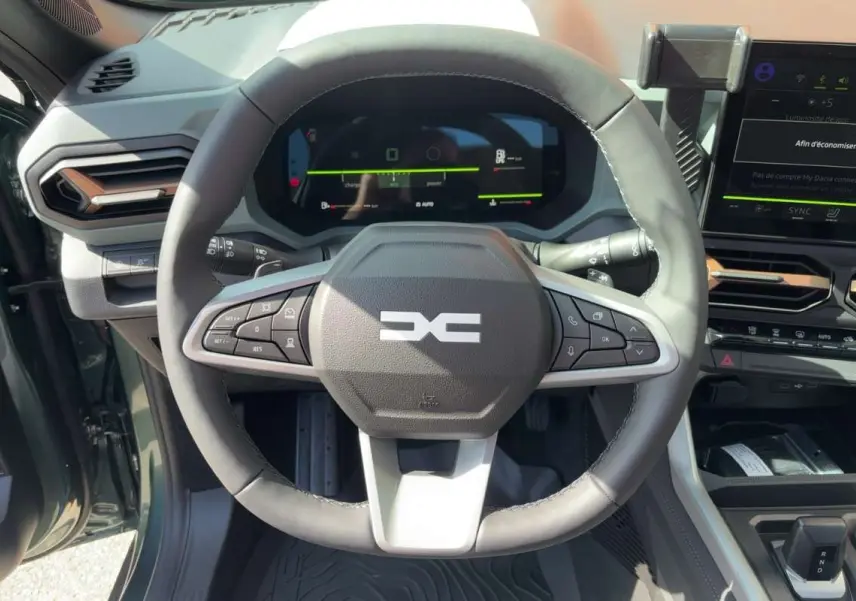 Vue intérieure centrée sur le volant cuir du Dacia Bigster vert cèdre avec tableau de bord digital et écran tactile.