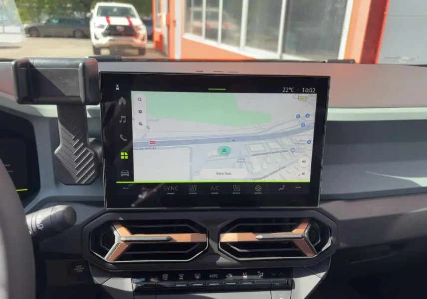 Vue intérieure du tableau de bord du Dacia Bigster Hybrid-G 150, écran tactile GPS et aérateurs hexagonaux noirs et bronze.