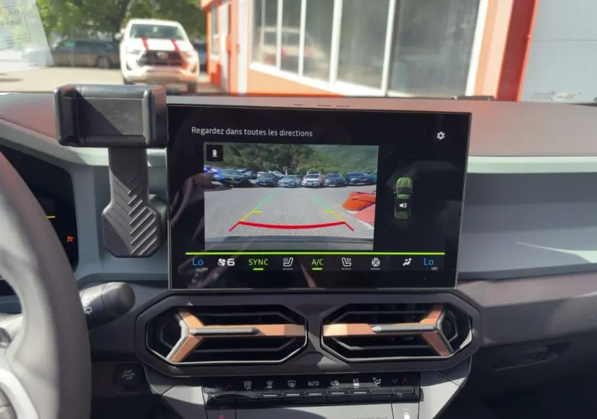 Vue intérieure du tableau de bord du Dacia Bigster Hybrid-G 150 4x4, écran central affichant la caméra de recul.